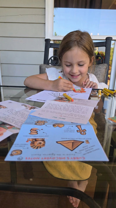 Ruby, 4, smiling while colouring in her Cubby's Discovery Notes activity sheet